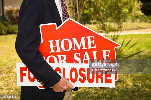 man real estate agent holds foreclosure real estate signs. home. - foreclosure stock pictures, royalty-free photos & images