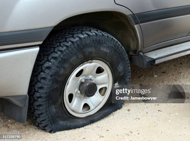 a flat tire deflating on an unpaved road - flat tyre stock pictures, royalty-free photos & images