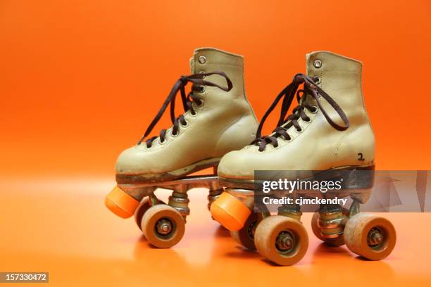 pair of orange and brown four-wheel rollerblades with laces - roller-skating stock pictures, royalty-free photos & images