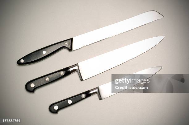 three kitchen knifes on grey background - bread knife stock pictures, royalty-free photos & images