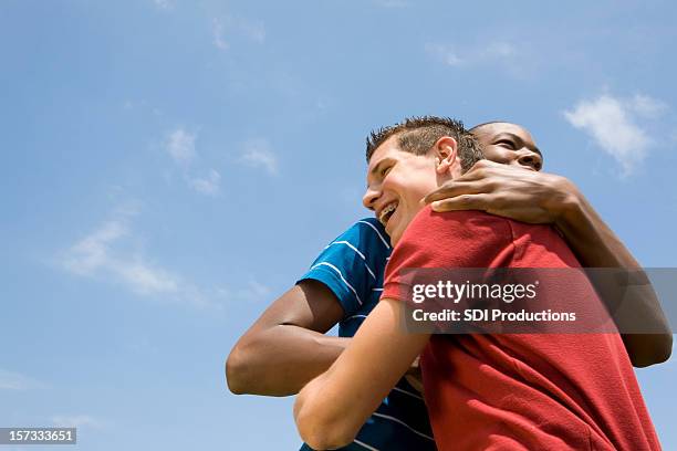 deux gars amis embrassant l'autre sous le ciel bleu - blue sky friends photos et images de collection