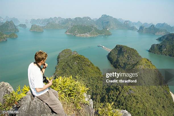 male photographer looking at a view of halong bay, vietnam - halong bay stock pictures, royalty-free photos & images