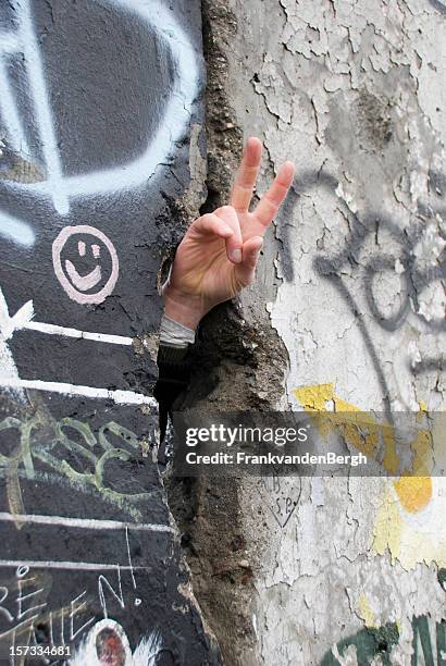 hand making peace sign at berlin wall - berlin wall stockfoto's en -beelden
