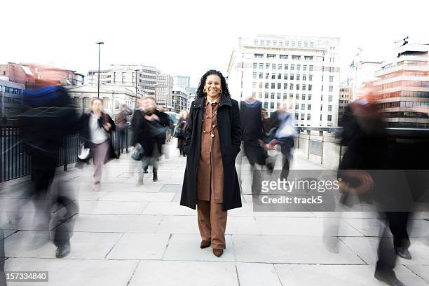 confident black-british business woman among the london commuter crowds - lange sluitertijd stockfoto's en -beelden