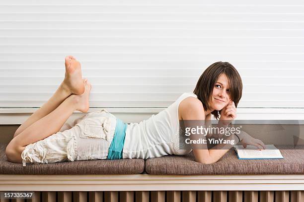 teenage woman reading in college dorm or residential house structure - cute college girl stockfoto's en -beelden
