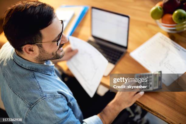 obenansicht eines glücklichen geschäftsmannes, der im homeoffice an finanzen arbeitet. - taschenrechner stock-fotos und bilder