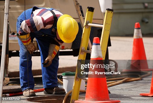 Construction Worker Looking Down man hole. Construction Worker Looking Down man hole.