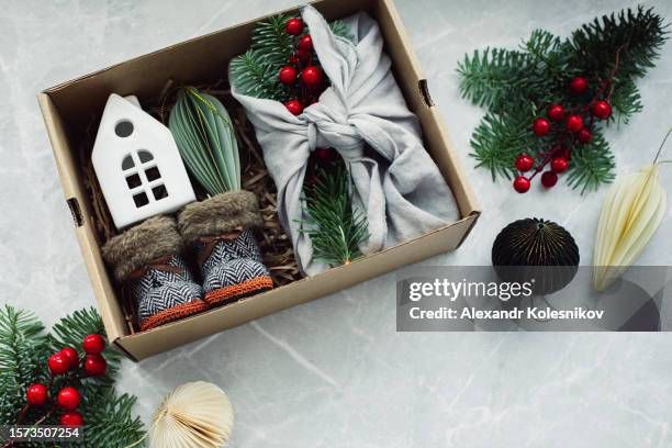 christmas furoshiki gift, white caramic house and cute small boots. zero waste christmas concept. flat lay - white house christmas stock pictures, royalty-free photos & images