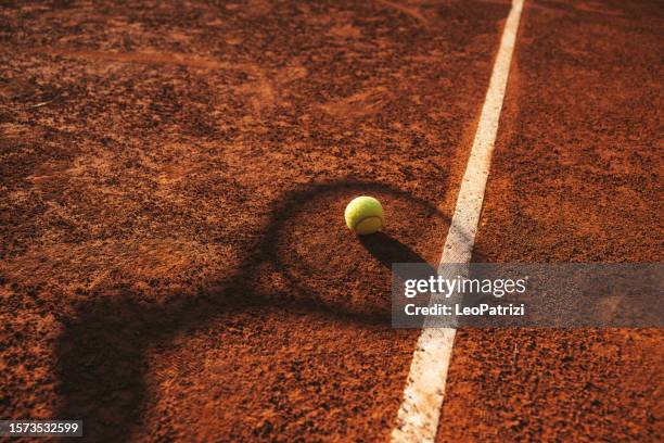 tennis racket shadow shape and tennis balls on a clay court - baseline stock pictures, royalty-free photos & images