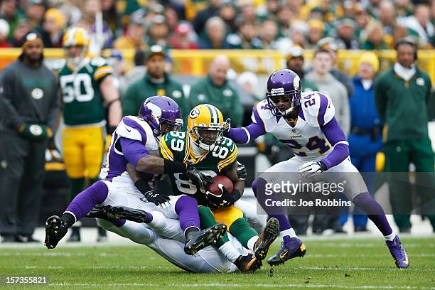 James Jones of the Green Bay Packers gets tackled by Erin Henderson and A.J. Jefferson of the Minnesota Vikings during the first half of the game at...