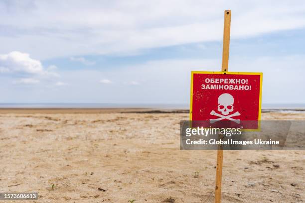Warning sign “Caution! Mines!” stands on a shore of a waterbody shallowed after the explosion of the Russian-controlled Kakhovka HPP on June 13, 2023...