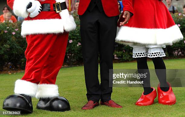 In this handout photo provided by Disney, a close-up photo shows actor Nick Cannon's sparkling red holiday shoes as he stands with Mickey Mouse and...