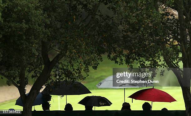 Members of the gallery hold umbrellas in the stands around the ninth green during the final round of the Tiger Woods World Challenge Presented by...