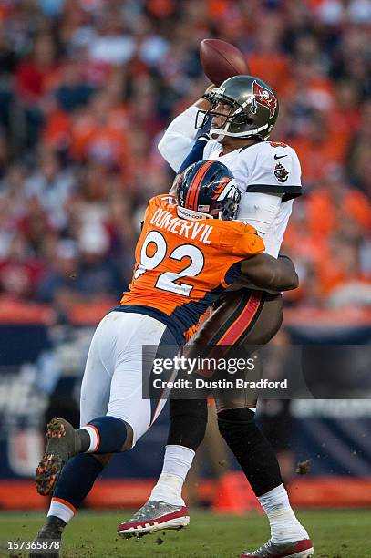 Quarterback Josh Freeman of the Tampa Bay Buccaneers hurries to get the ball away as he is hit by defensive end Elvis Dumervil of the Denver Broncos...