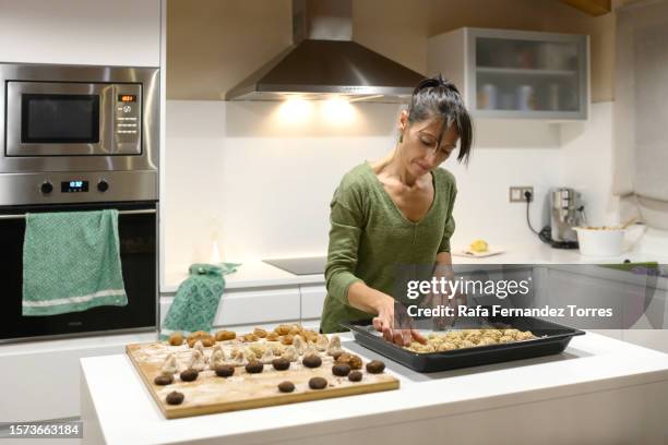 woman in kitchen making panellets by placing on tray - panellets fotografías e imágenes de stock
