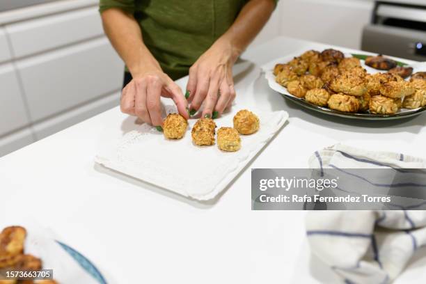 woman in kitchen making panellets by placing on tray - panellets fotografías e imágenes de stock
