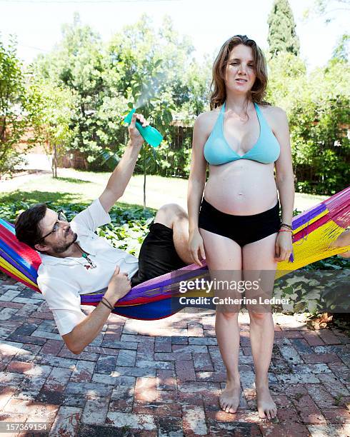 husband spritzing pregnant wife in hammock - hot wife stockfoto's en -beelden