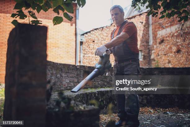 man using leaf blower to clean back yard - noise machine stock pictures, royalty-free photos & images