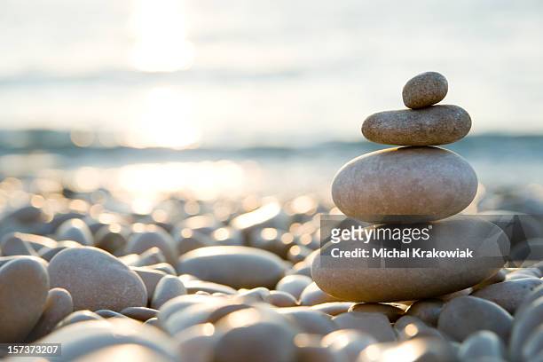 balanced stones on a pebble beach during sunset. - simplicity stock pictures, royalty-free photos & images