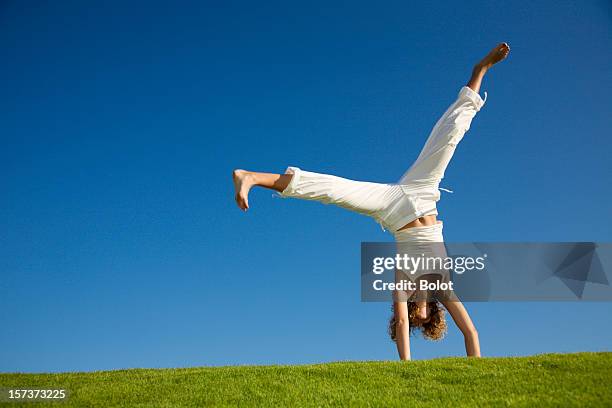 jeune femme en train de faire la roue sur de l'herbe - équilibre sur les mains photos et images de collection