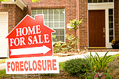 Real Estate Sign in yard of foreclosure house. For sale.