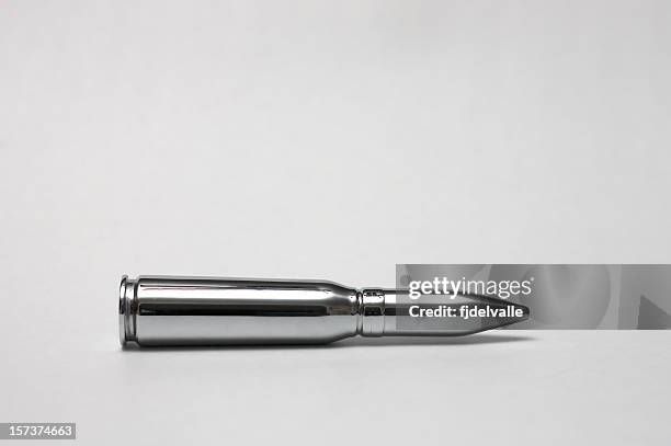 shiny chrome bullet against gray background - kogel stockfoto's en -beelden