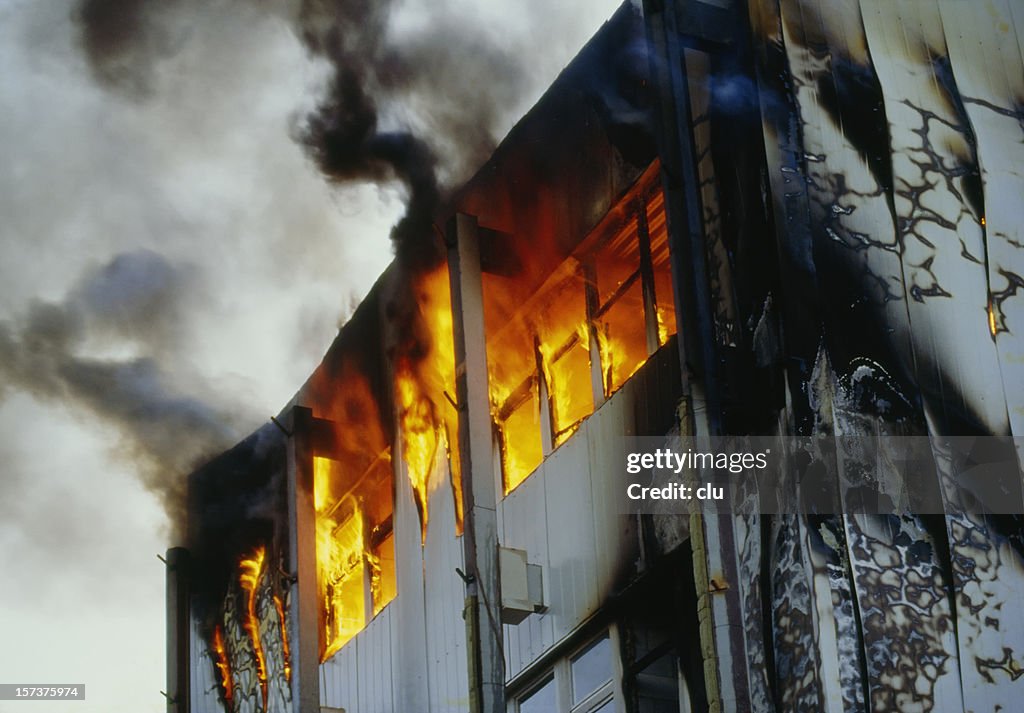 Burning house upper floor and and ascending black smoke