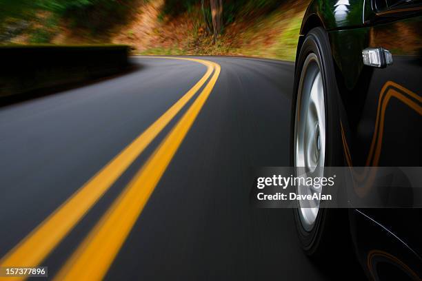 a black sports car driving around a curve - corner marking stockfoto's en -beelden