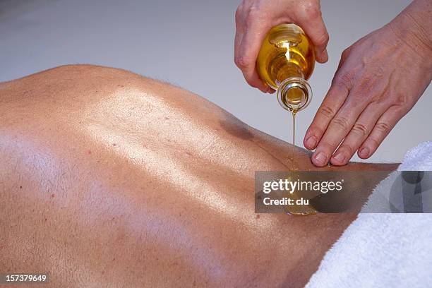 massage for man: masseuse pouring oil on the back - oily skin stock pictures, royalty-free photos & images