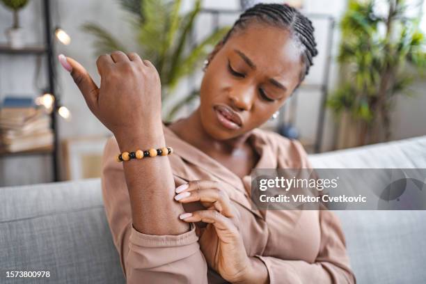 mujer negra rascándose la piel seca y con picazón en el antebrazo - antebrazo fotografías e imágenes de stock