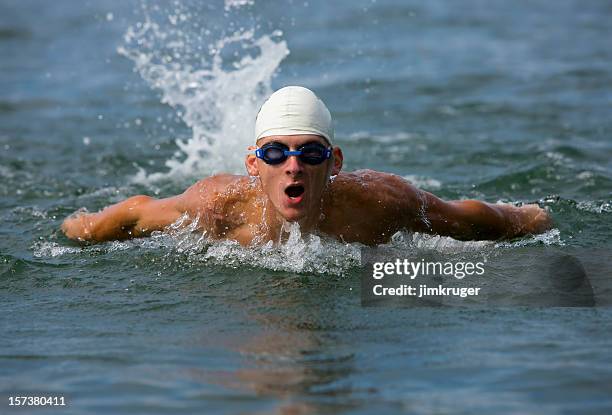 competitive male swimmer in water mid-stroke. - surfacing stock pictures, royalty-free photos & images