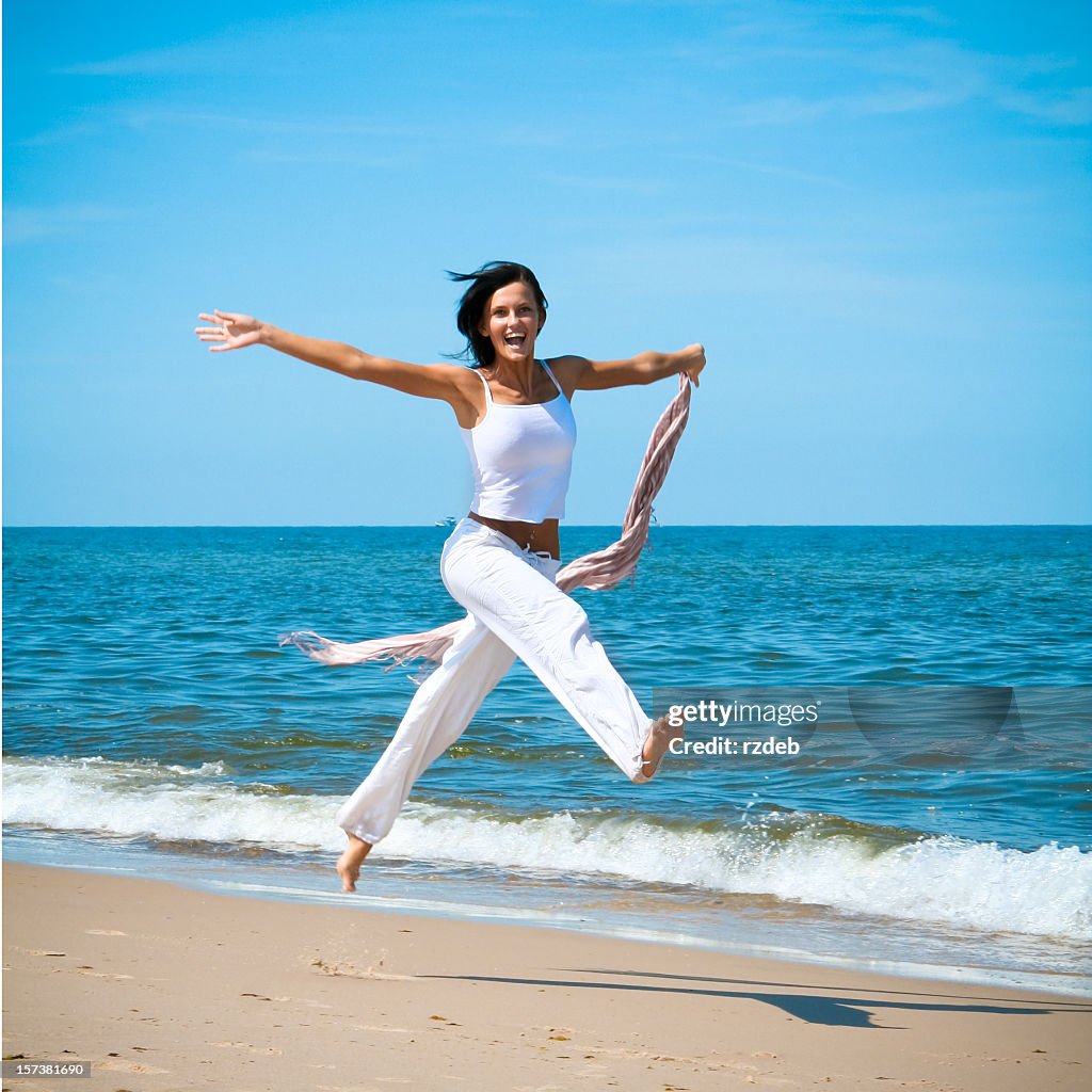 Woman jumping happily on the beach