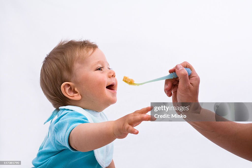 A parent spoon feeding their baby