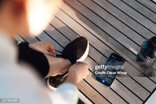 young woman tracking time and distance with running app on smartphone - rezar stock pictures, royalty-free photos & images