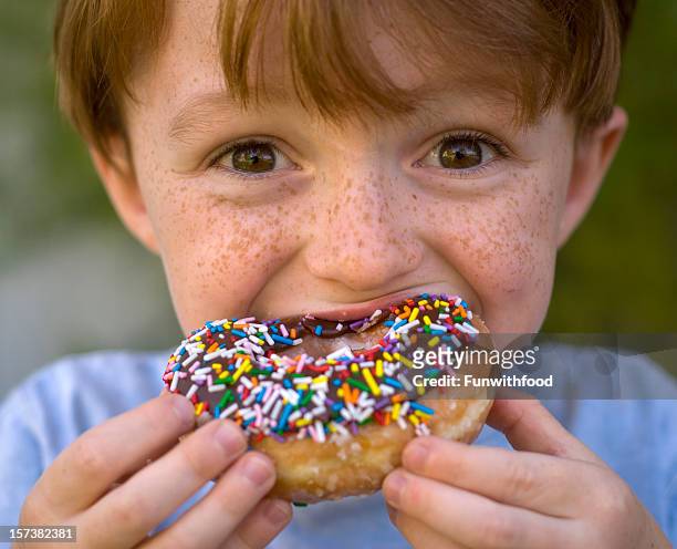 boy eating chocolate donut, unhealthy child holding breakfast food - biting donut stock pictures, royalty-free photos & images