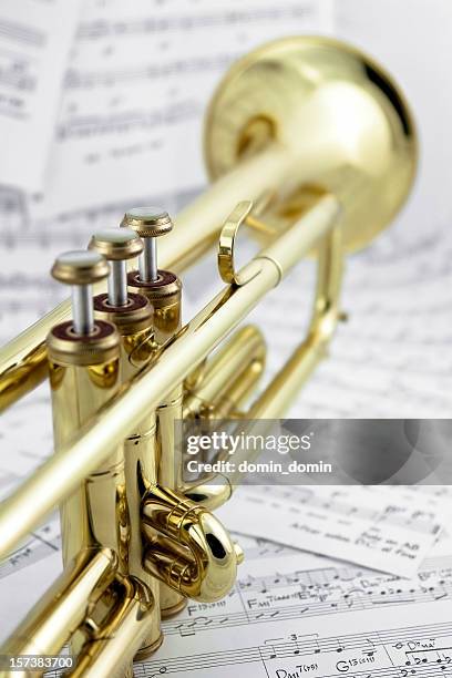 close-up of golden trumpet lying on music notes, back view - blaasinstrument stockfoto's en -beelden