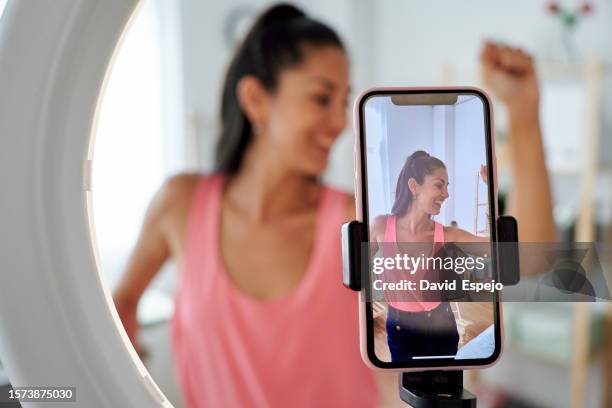 woman smiling and dancing while making a video for tiktok with mobile phone. - dance challenge stock pictures, royalty-free photos & images