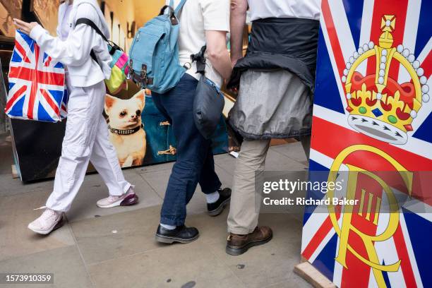 Visitors to the capital and Londoners walk past tourist souvenir hoardings at Piccadilly Circus in the West End, on 25th July 2023, in London,...