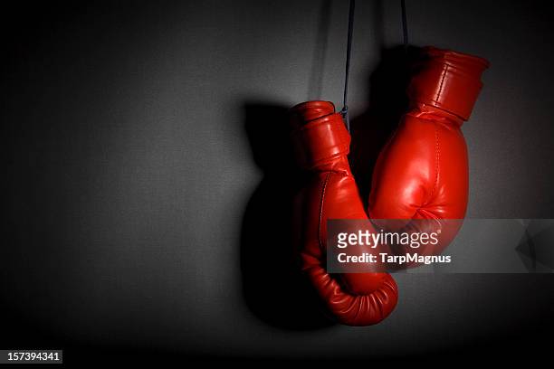red boxing gloves hanging against grey wall - boxing glove 個照片及圖片檔