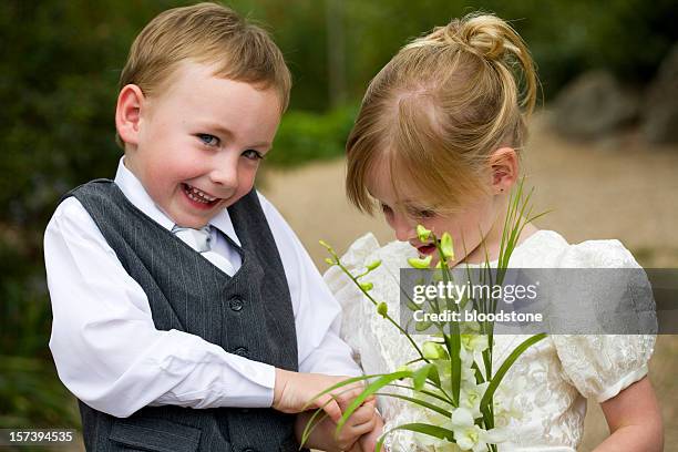 little page boy holding hands with flower girl outside - pageboy stockfoto's en -beelden