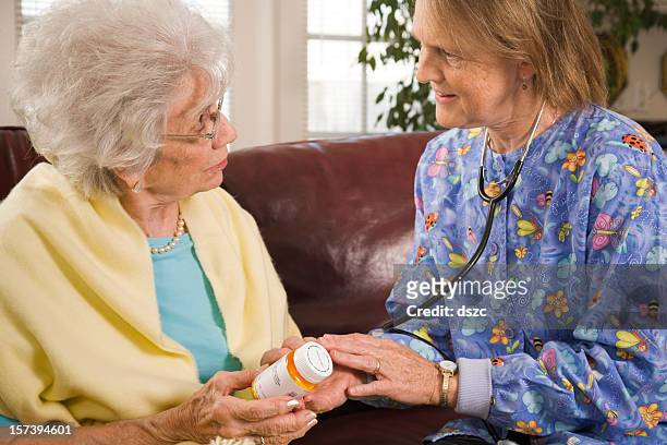 home healthcare medical professional helps senior woman with medicine - preventive care stock pictures, royalty-free photos & images