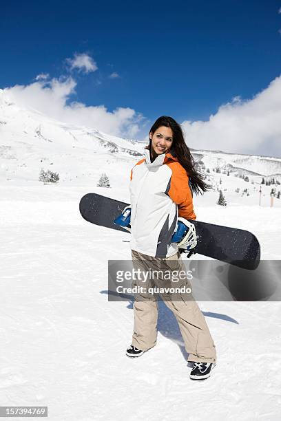 beautiful young woman carrying snowboard on sunny mountain day - combat trousers stock pictures, royalty-free photos & images