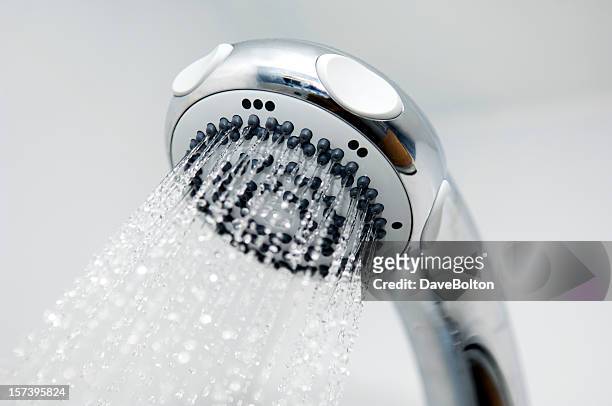 a close-up of a silver chrome shower head spouting water - shower head stock pictures, royalty-free photos & images
