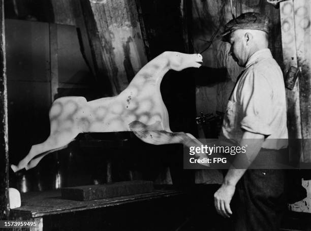 Man spray painting a dapple grey rocking horse at the Converse Toy Company in Winchendon, Massachusetts, circa 1935. Such a high volume of toys are...