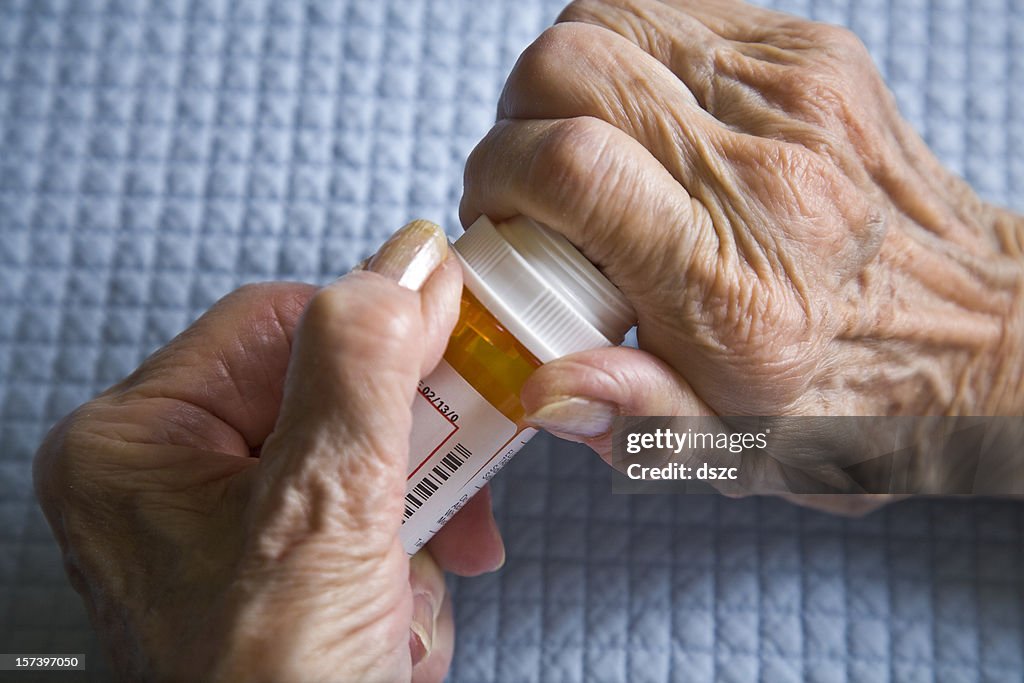 Arthritis hands trying to open prescription medicine pill bottle