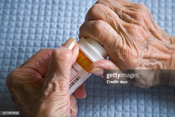 arthritis hands trying to open prescription medicine pill bottle - arthritic hands stock pictures, royalty-free photos & images