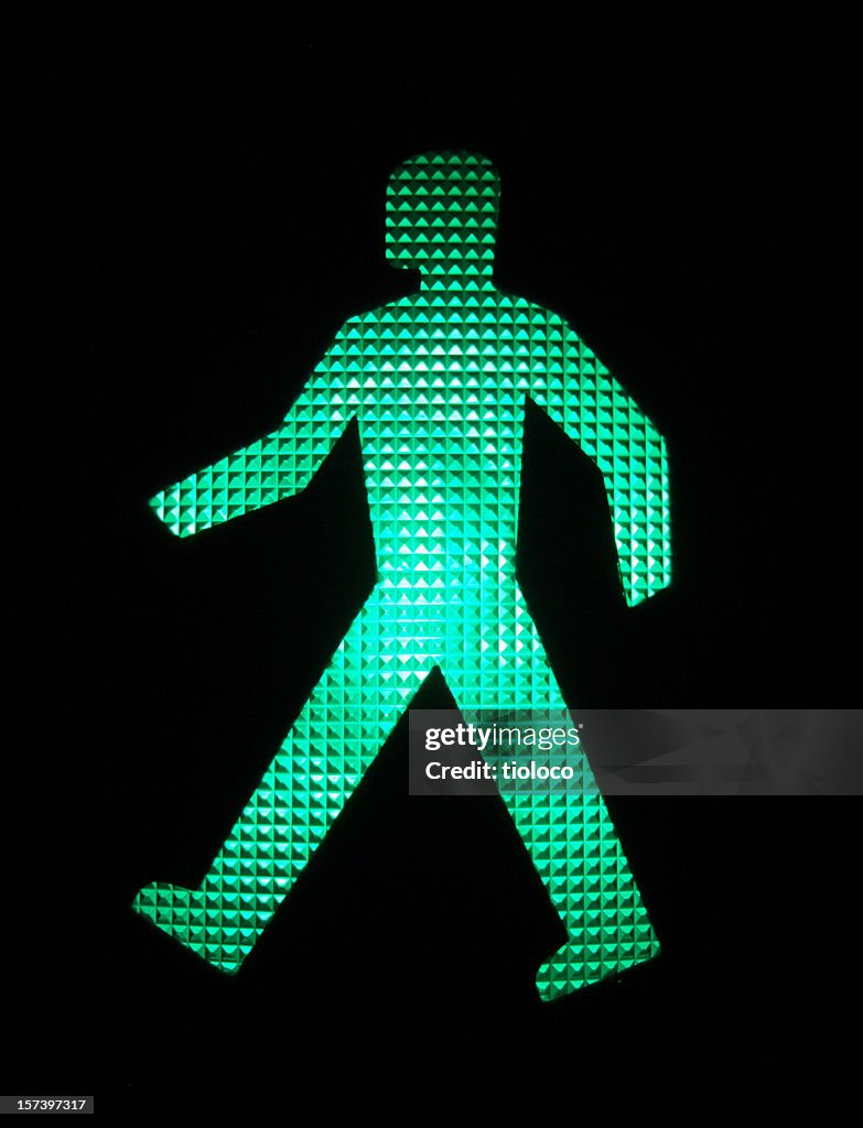An illuminated green LED image of a walking person