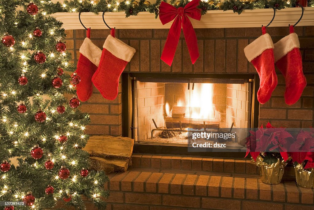 Christmas tree and decor around the fireplace with blazing fire