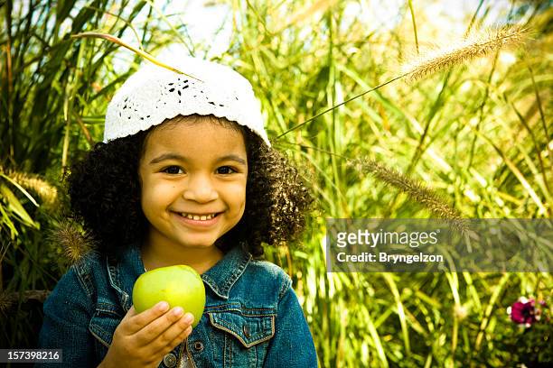 kleines mädchen mit grünem apfel - child holding apples stock-fotos und bilder