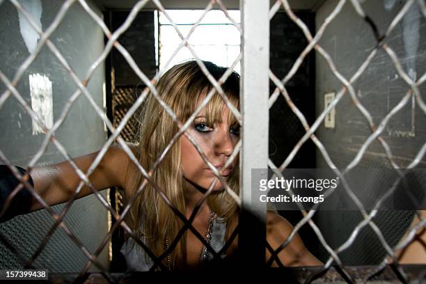 tough looking girl behind bars - female victim stock pictures, royalty-free photos & images